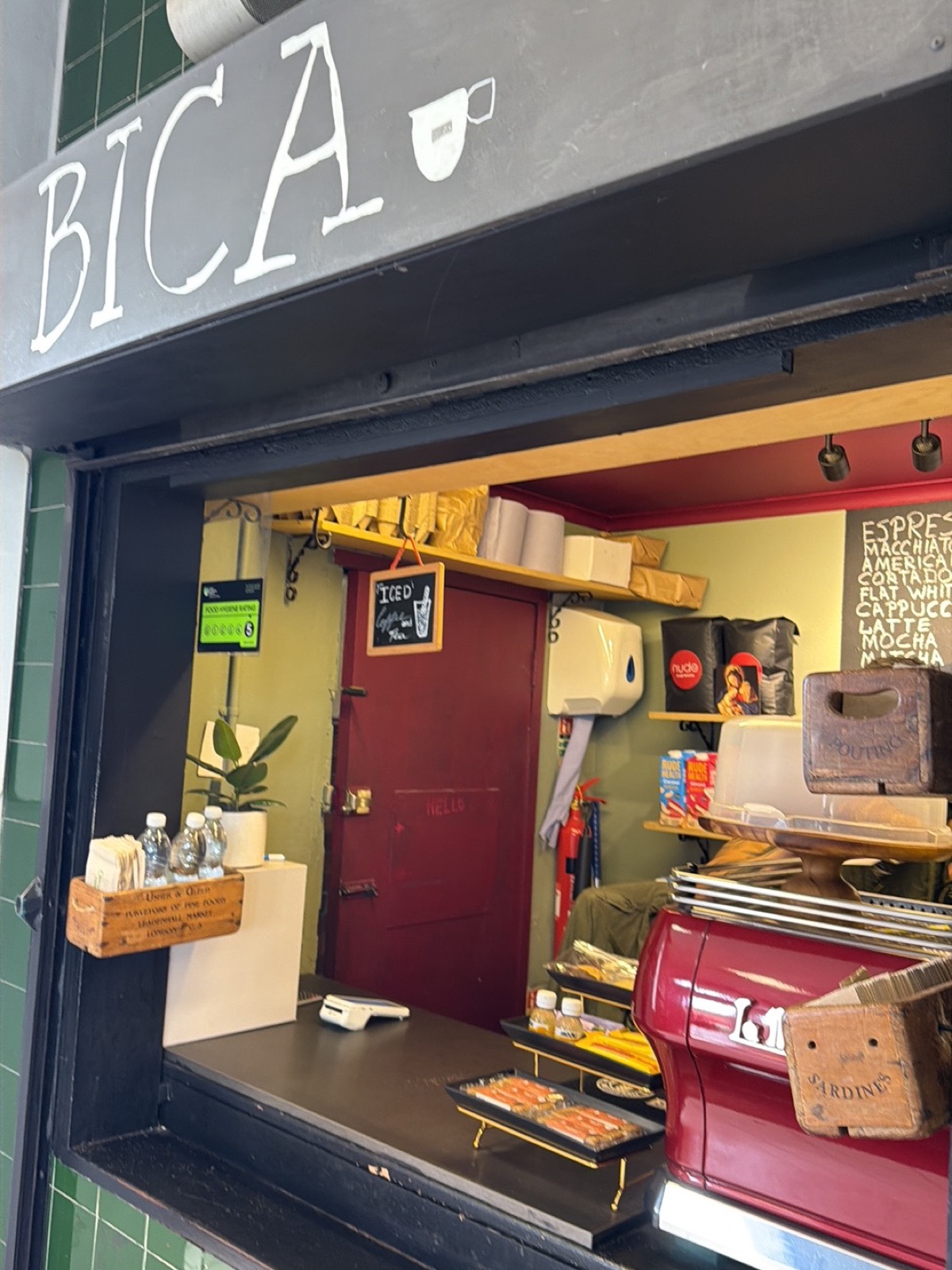 The red espresso machine and counter seen through the serving hatch