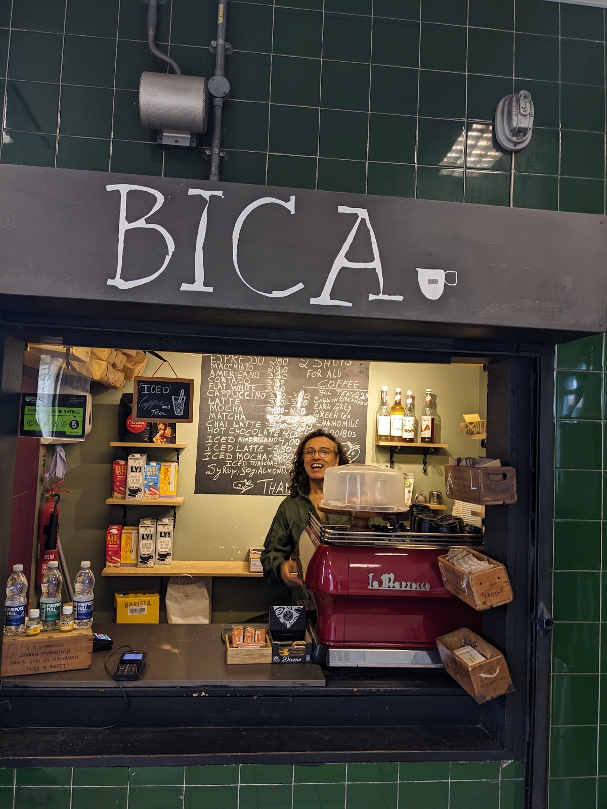 The green-tiled Bica counter with stocked shelves and the barista at work